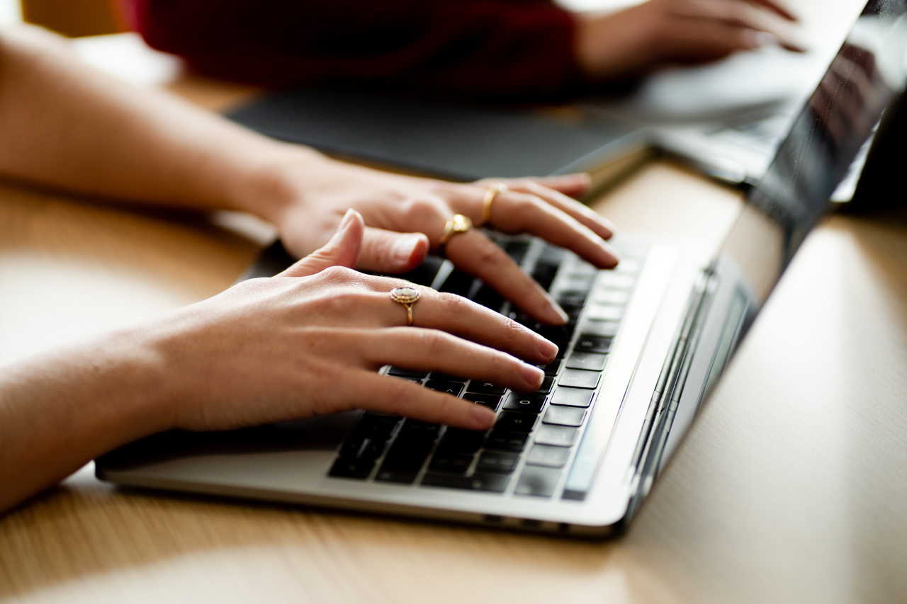 Close up of a woman's hands typing on a laptop